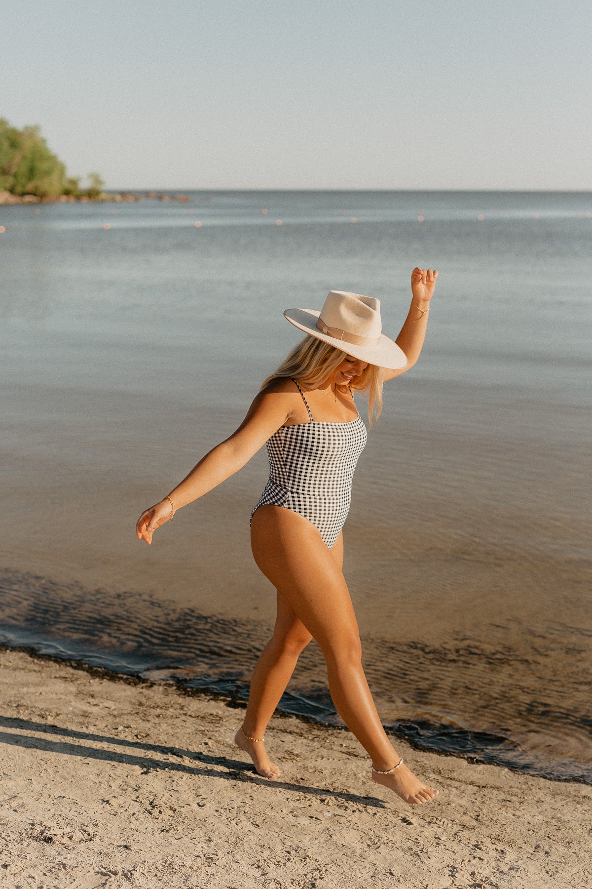 Influencer Nicole Zajac wears North American swimwear brand Prairie Swim chic straight neckline black and white gingham check print one piece swimsuit with adjustable straps, cinched waist and high cut legs